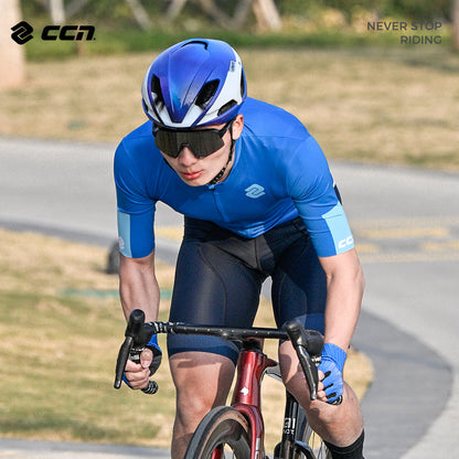 A man cycling wearing a blue short-sleeved cycling jersey with a white helmet and the logo 'CCN' on the jersey.